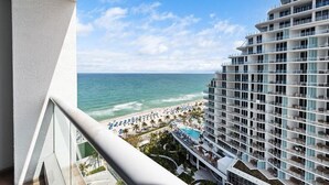 A high-rise hotel with a beach view, multiple balconies, and a pool area.