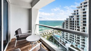 A balcony with a view of a beach and a hotel building.