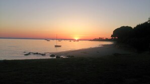 Ein Strand mit Booten und einem Sonnenuntergang.