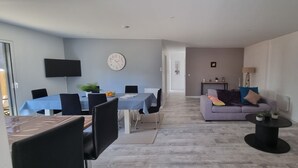 Ein modernes Wohnzimmer mit Essbereich, einer Couch und einem an der Wand befestigten Fernseher.