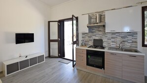 Une cuisine moderne équipée d’un four encastré, d’un évier et d’une cuisinière. Une porte-fenêtre coulissante donne accès à un balcon.