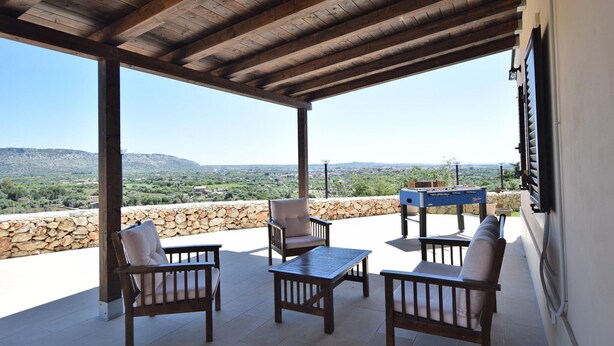 Une terrasse extérieure avec des meubles en bois, une table et une vue sur un paysage montagneux.