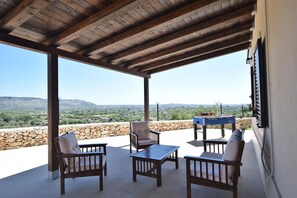 An outdoor patio with wooden furniture, a table, and a view of a mountainous landscape. - Holiday Home Floridia with Private Pool (Floridia)