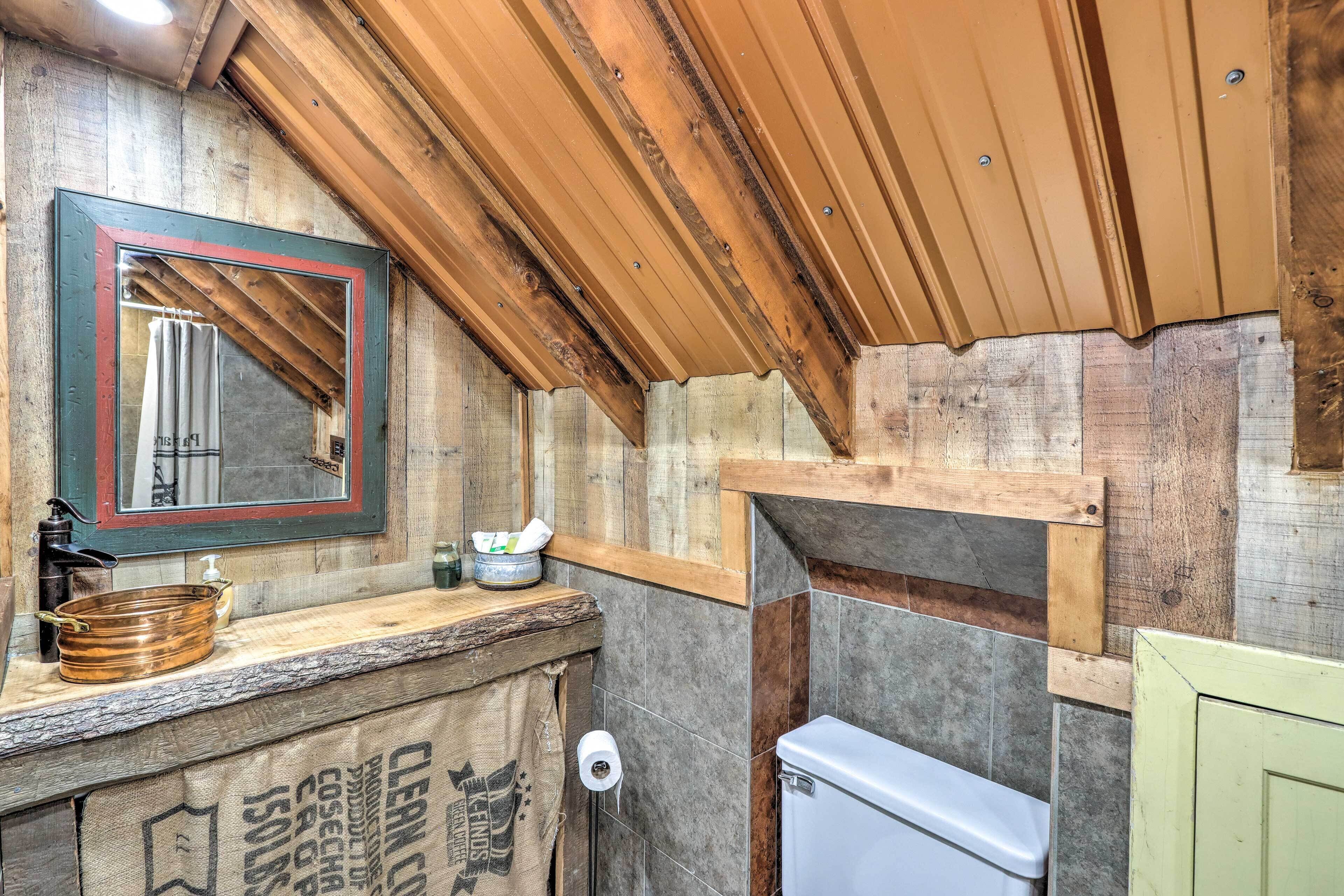 Une salle de bain rustique avec un meuble-lavabo en bois, un miroir avec un cadre rouge, des toilettes et un distributeur de serviettes.