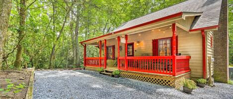 A wooden cabin with a red porch, surrounded by trees.