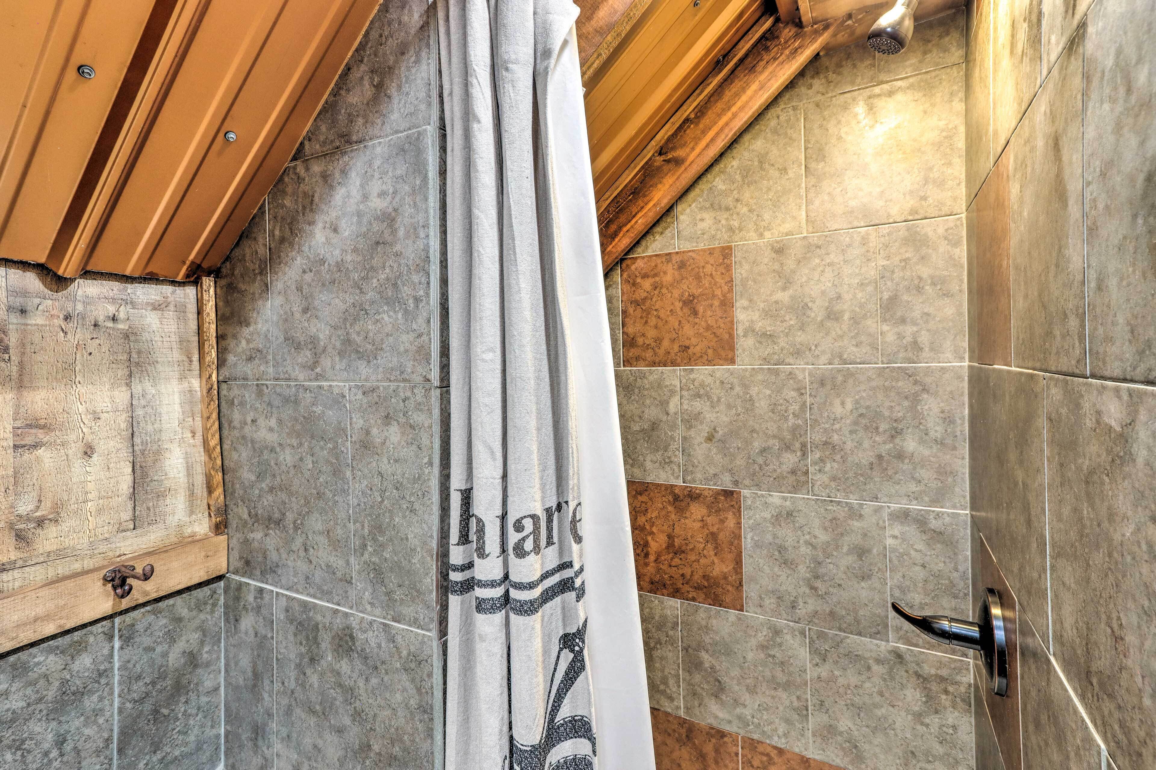 Douchegedeelte met houten plafond, betegelde wanden en een douchegordijn met gedeeltelijk zicht op het woord 'share'.
