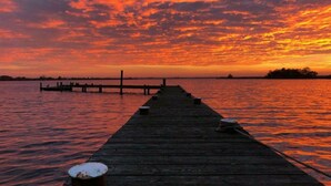 A wooden pier extending into calm water with a sunset in the background. - Wismarer-heckflosse (Wismar)