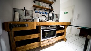 A kitchen with a wooden countertop, a built-in oven, and a coffee maker. - Wismarer-heckflosse (Wismar)