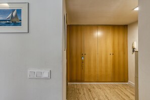 Um corredor com um guarda-roupa de madeira, um quadro na parede e um interruptor de luz.