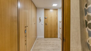 A hallway with wooden wardrobes, a tiled floor, and a door at the end. - 'Loft Palamós' Apartment with A/C (Palamos)