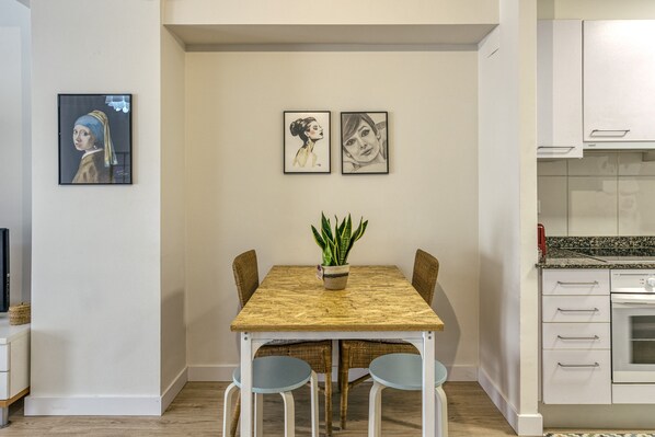 Un espace repas comprenant une table, des chaises, une plante en pot et des œuvres d’art murales.