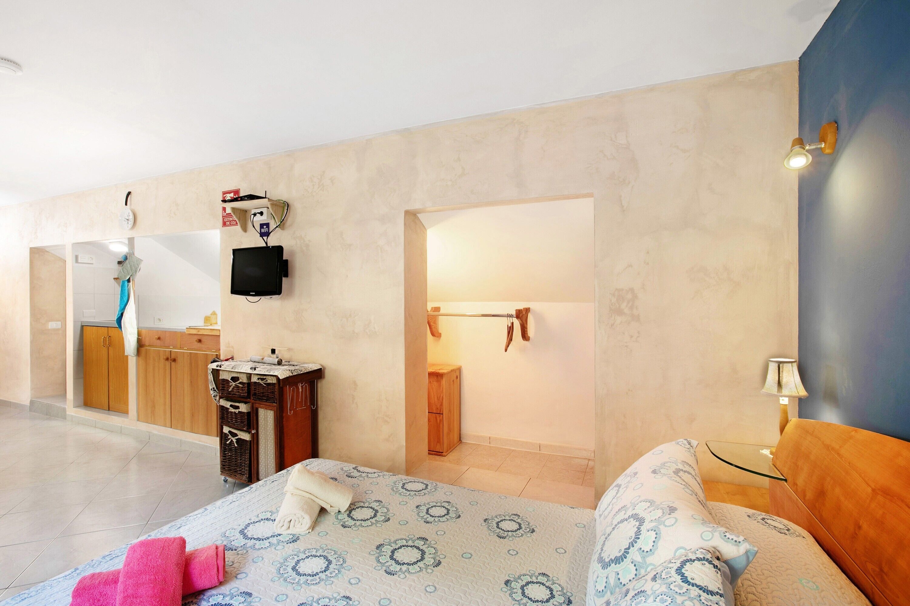 A bedroom with a bed, a bedside table, a mirror, a wardrobe, and a bathroom visible through an open door.