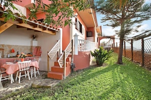Una casa con un patio, una mesa de comedor cubierta con un mantel a cuadros rojo y blanco, y una escalera que conduce al piso superior.