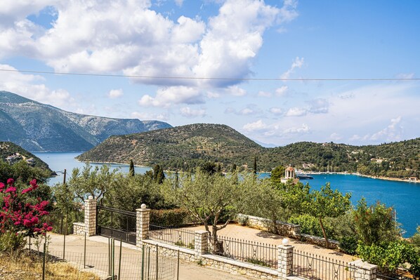 A coastal landscape with mountains, a clear sky, and a body of water.