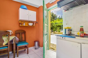 A compact kitchen with a dining area, a trash bin, and a view of the outdoors. - Studio 'Veronis 3' with Sea View, Shared Pool & Wi-Fi (Ithaca)