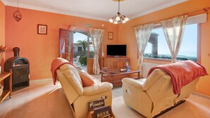 A living room with two leather sofas, a television, a wooden cabinet, and a fireplace.