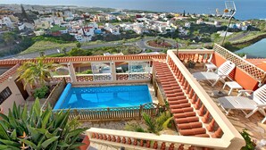 A rooftop pool with a view of a coastal town.