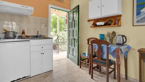 Una cuina compacta amb zona de menjador, un armari blanc i una vista a través d'una porta oberta.
