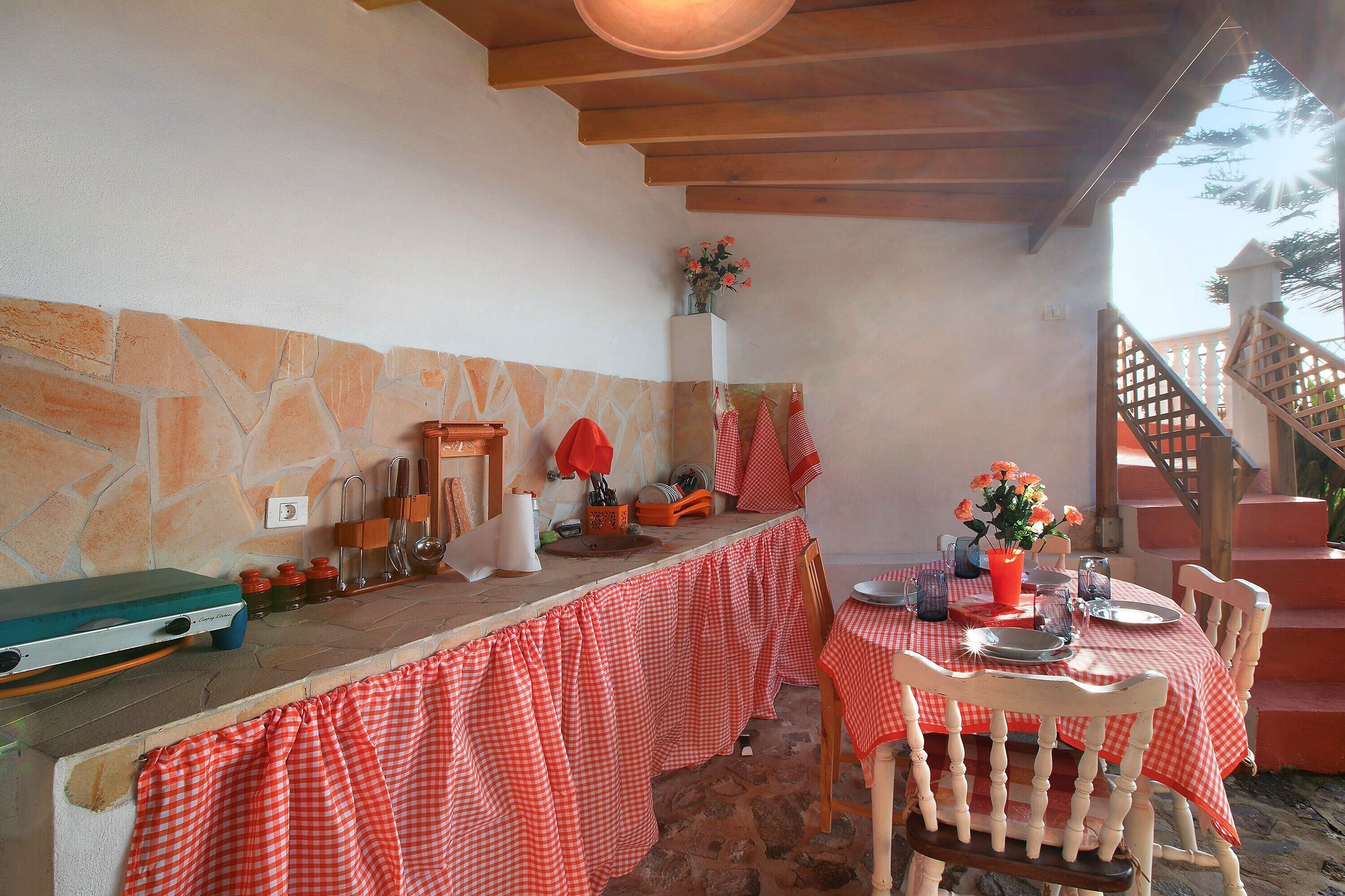 A stone wall, a wooden table with a checkered tablecloth, and a chair.