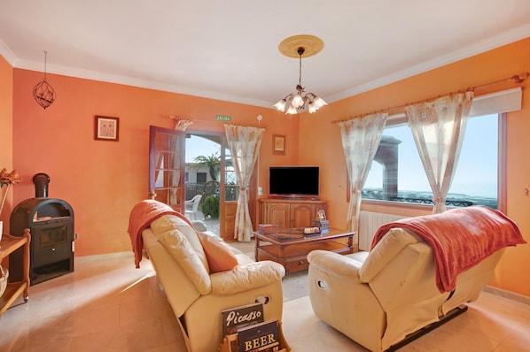 A living room with two leather sofas, a television, a wooden cabinet, and a fireplace.