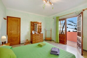 A bedroom with a bed, dresser, and a view through an open door.