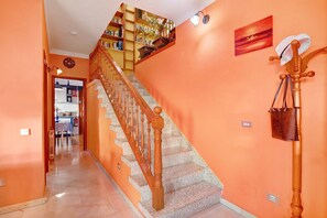 A staircase with wooden balusters, a wall-mounted coat rack, and a bookshelf with books and decorative items.