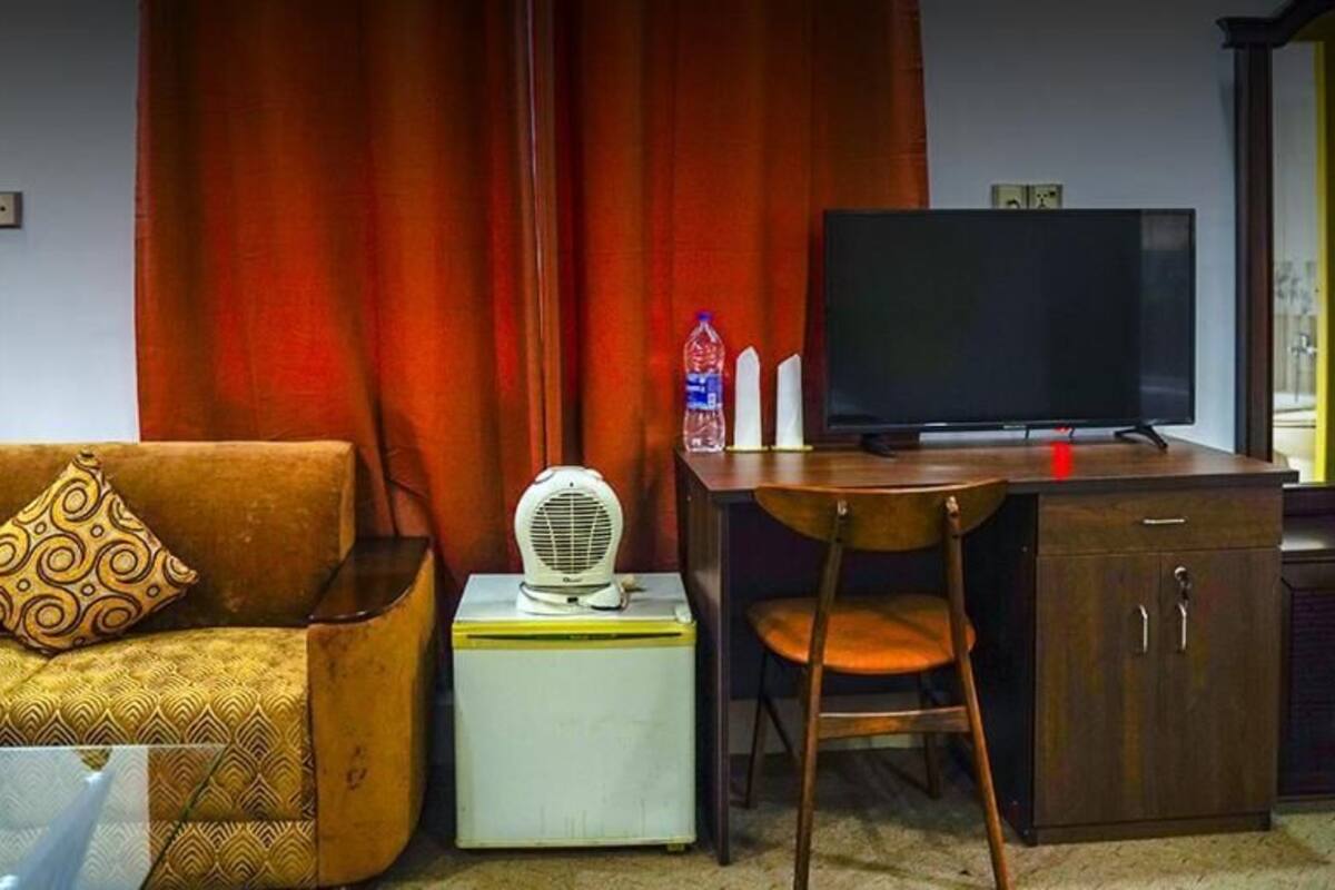 Een woonkamer met een bank, een kleine tafel met een ventilator, een televisie en een kast.