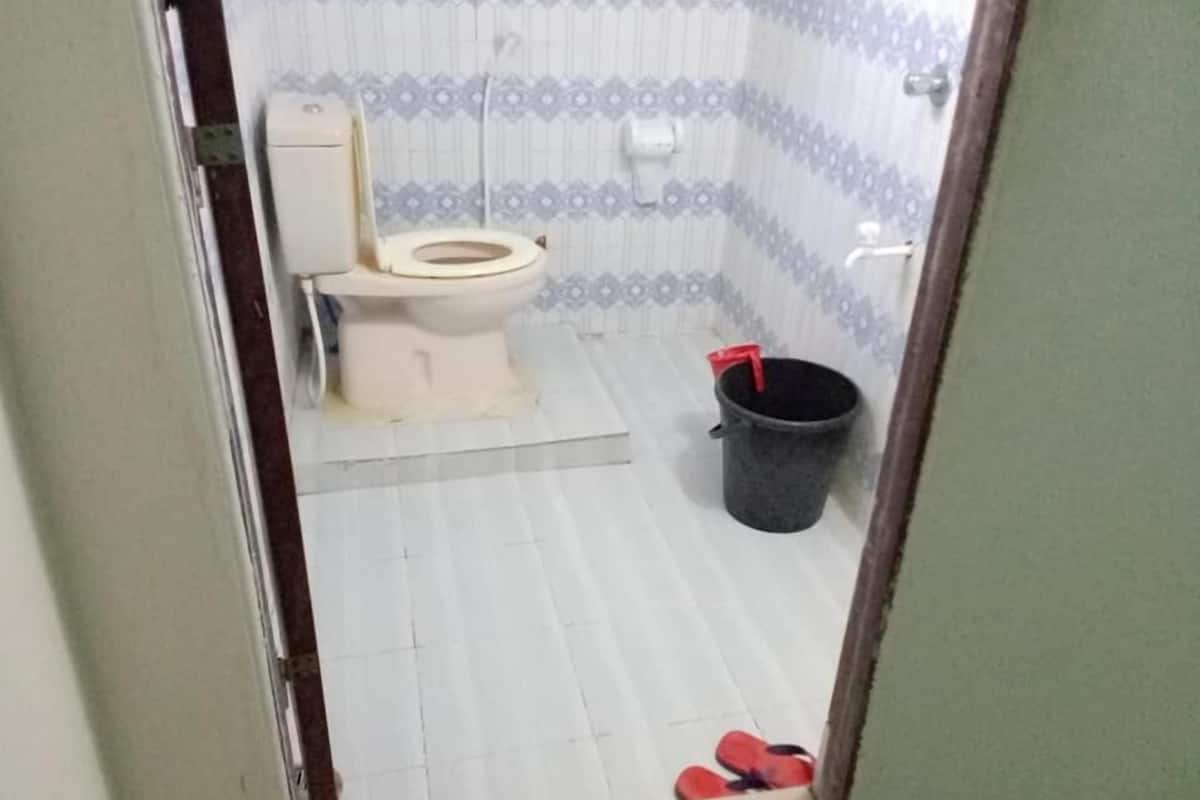Een badkamer met een toilet, een emmer en een paar slippers.
