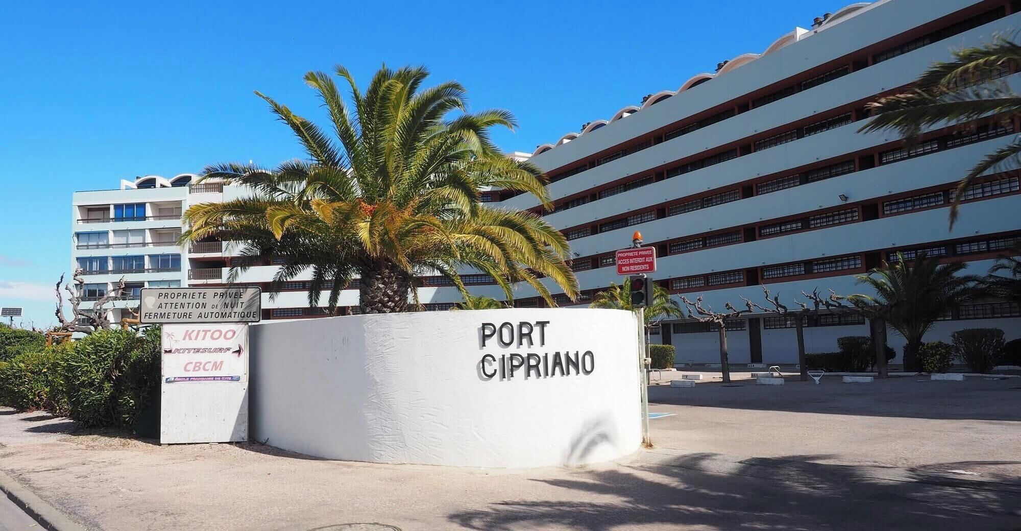 A building with a sign reading 'PORT CIPRIANO' and another sign indicating 'PROPRIETE PRIVÉ ATTENTION DE NUIT FERMETURE AUTOMATIQUE'.