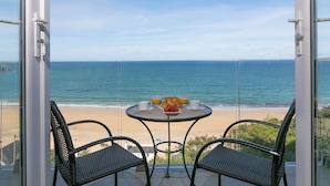 Un balcón con una mesa y dos sillas que da a la playa.