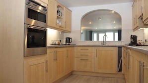 Una cocina moderna con electrodomésticos de acero inoxidable, armarios de madera y horno empotrado.