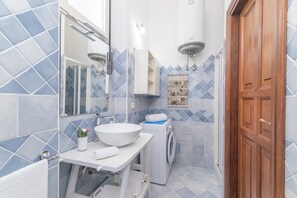 Une salle de bain équipée d’un lavabo, d’un miroir, d’un porte-serviettes et d’un lave-linge.