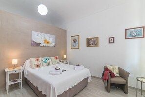 Un dormitorio con cama, mesitas de noche, una silla y decoración en la pared.