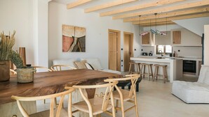 A spacious living area with a wooden dining table, wicker chairs, and a kitchen in the background. - Adrias Villa (Kefalonia)