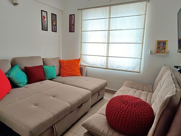 A living room with two sofas, a large window, and wall-mounted artwork.