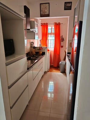 A kitchen with white cabinets, a stove, and a refrigerator.
