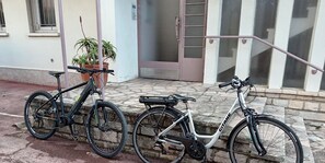 Bicycles parked outside a charming building with a white exterior and a brown door.