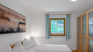 Une chambre à coucher avec un lit, une fenêtre avec des rideaux, un tableau au mur et une porte coulissante.
