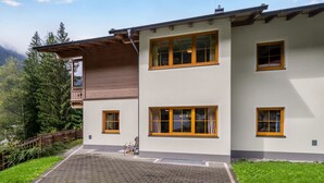 Une maison à deux étages avec une allée pavée et une terrasse en bois.