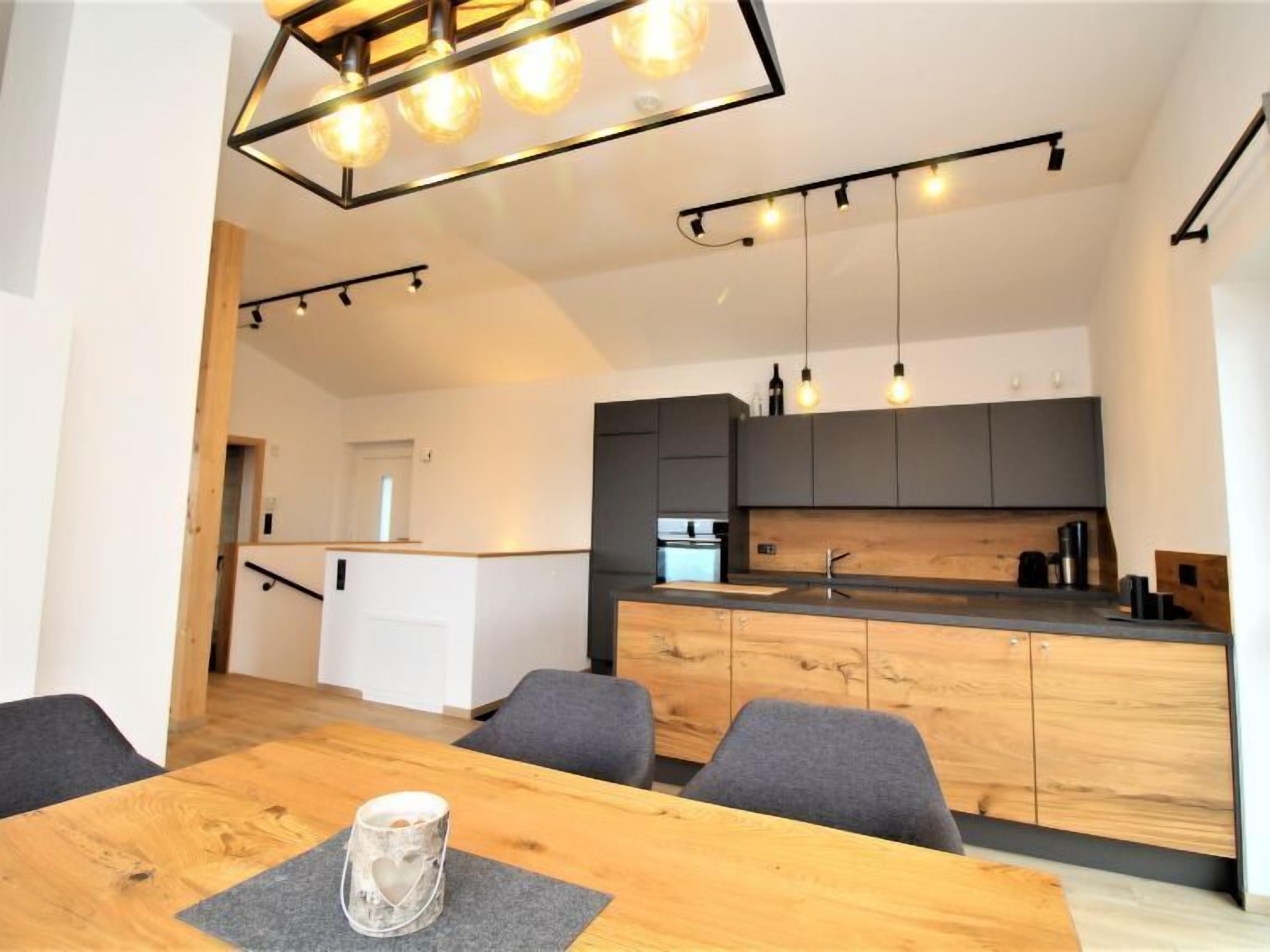 A modern kitchen with wooden cabinets, a central island, and pendant lighting.
