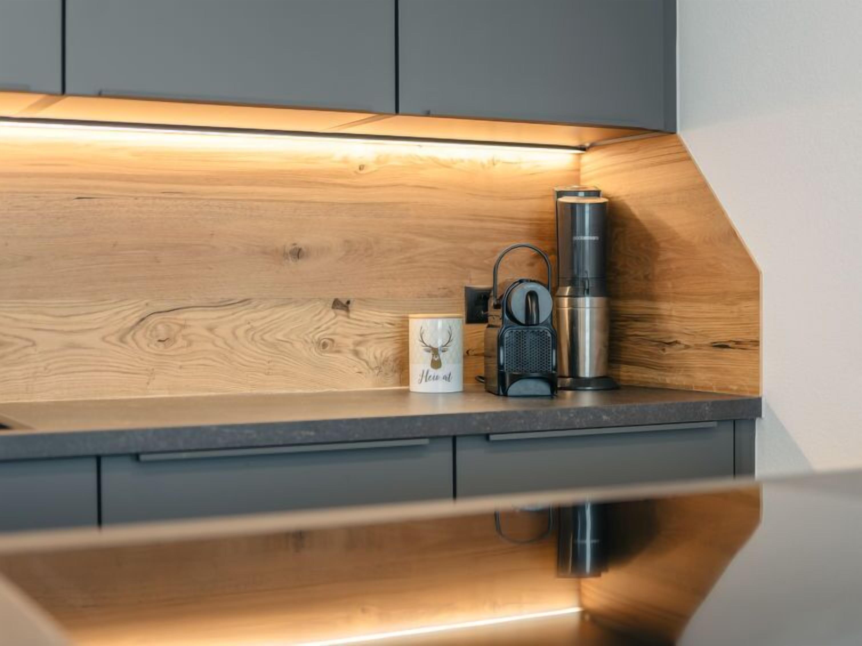 Een keukenblad met een houten achterwand, een koffiezetapparaat en een mok.