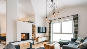 A modern living room with a fireplace, a sofa, a coffee table, and a TV mounted on the wall.
