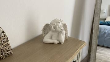 Une commode en bois sur laquelle est posée une statuette d’ange blanche.