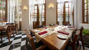 Uma sala de jantar com uma mesa de madeira grande posta para seis pessoas, rodeada por cadeiras de madeira.