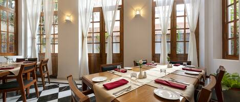 A dining area with a large wooden table set for six, surrounded by wooden chairs.