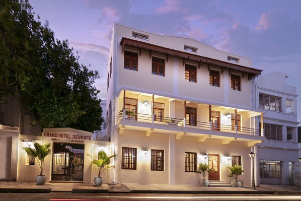 A multi-story hotel with a white facade, balconies, and potted plants. - Grand Hotel D' Europe (Puducherry)