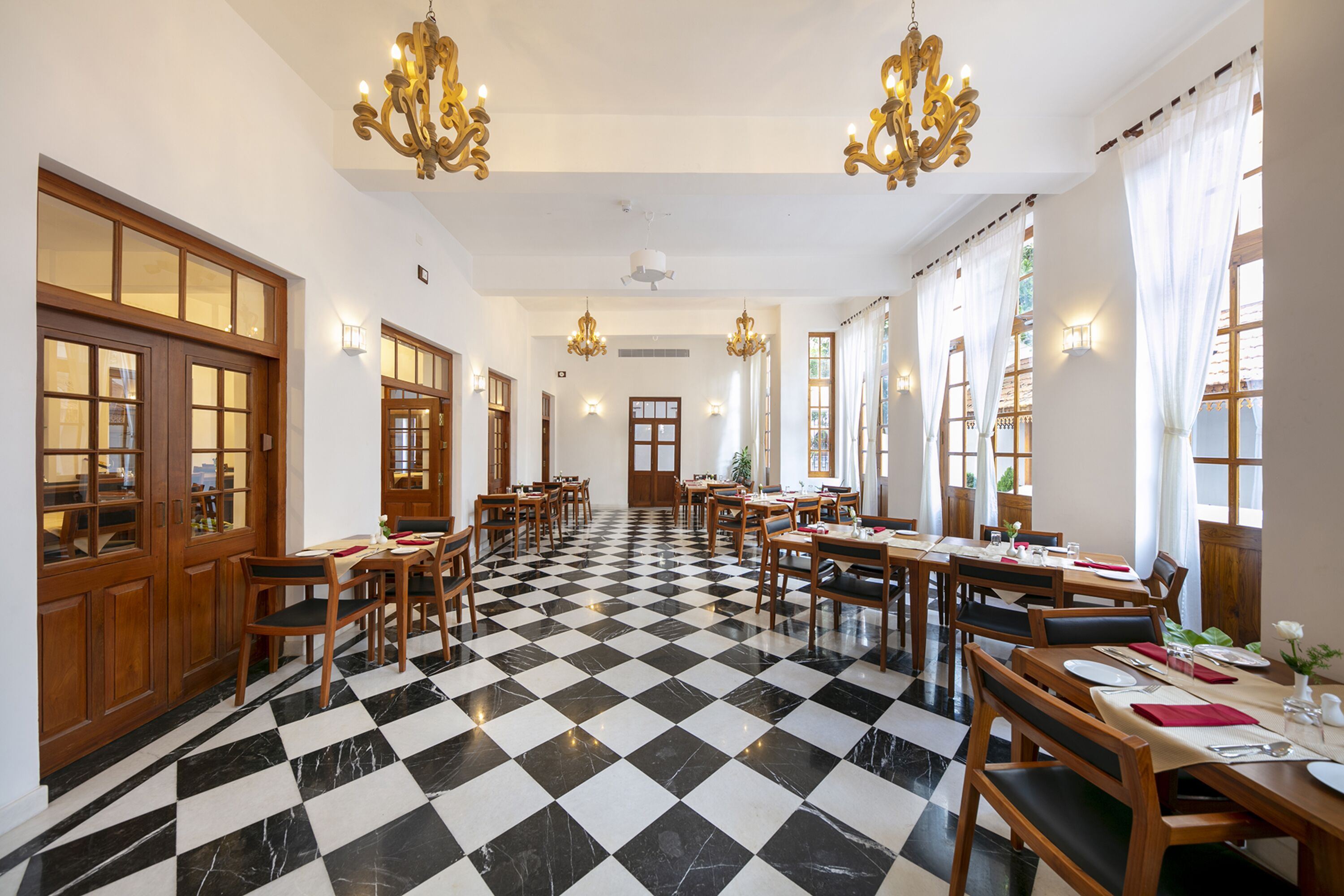 Un comedor de hotel con suelo a cuadros, mesas de madera y candelabros.