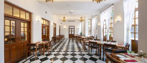 Un comedor de hotel con suelo a cuadros, mesas de madera y candelabros.