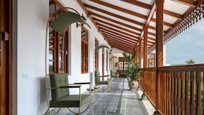 Uma área de estar coberta ao ar livre, com vigas de madeira e piso de azulejos.