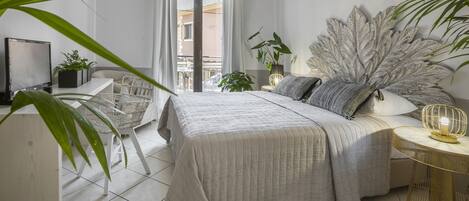 A modern bedroom with a bed, bedside tables, a desk, and a large plant.